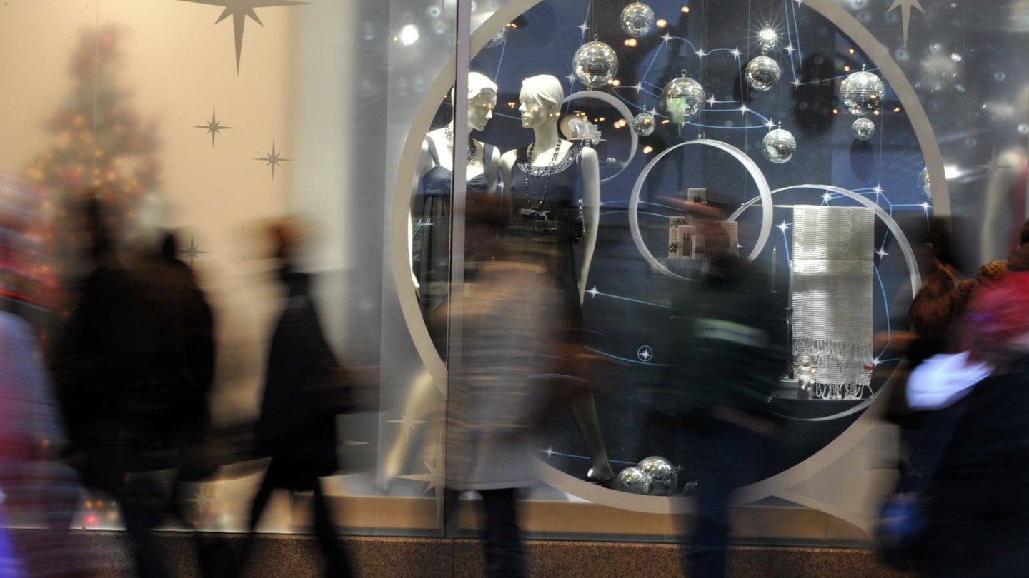 Passanten stehen in Freiburg am Schaufenster eines Kaufhauses.