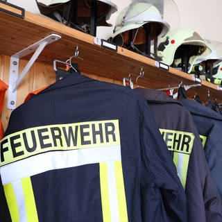 Einsatzkleidung der Feuerwehr hängt an einer Wand.