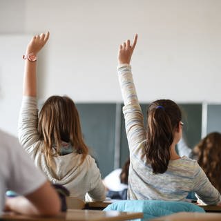 Schüler einer siebenten Klasse melden sich während des Deutschunterrichts in einem Gymnasium. 