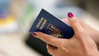 Eine Geflüchtete aus der Ukraine hält ihren Reisepass während der Registrierung in der Hand.
