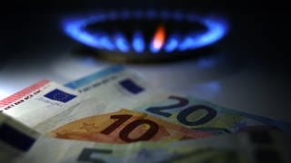 Gestelltes Bild zum Thema Gaspreise: Hinter Euro-Noten brennt an einem Herd eine Gasflamme. 