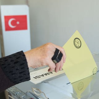 Eine Frau wirft in Stuttgart in einem Wahllokal vom türkischen Generalkonsulat einen Umschlag mit dem Wahlzettel in eine Wahlurne. 