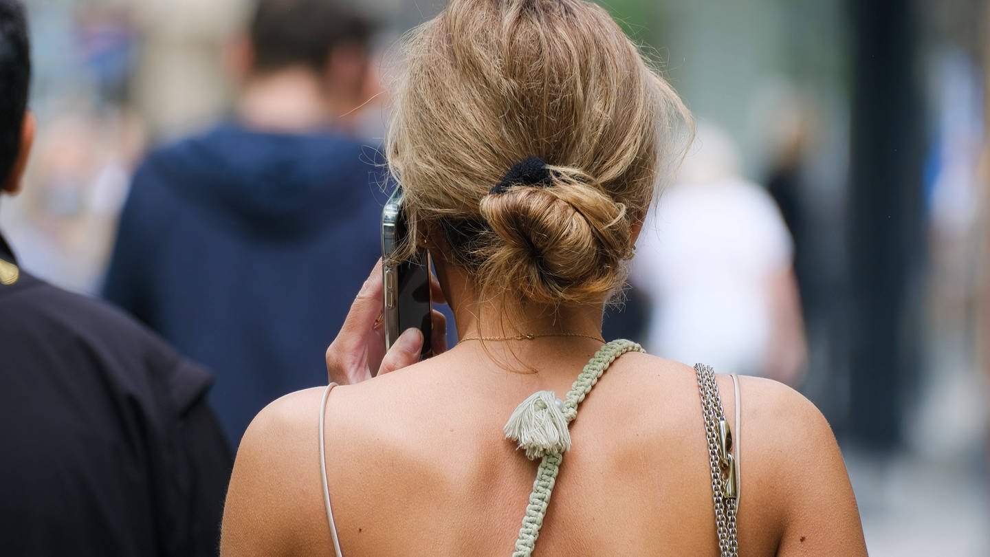Eine Frau mit dem Telefon am Ohr in der Stadt.