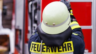 Ein Feuerwehrmann holt während einer Einsatzübung einer Freiwilligen Feuerwehr eine Leiter vom Dach eines Einsatzfahrzeugs.