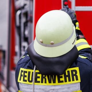 Ein Feuerwehrmann holt während einer Einsatzübung einer Freiwilligen Feuerwehr eine Leiter vom Dach eines Einsatzfahrzeugs.