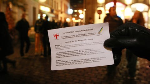 Ein Polizeibeamter zeigt am Samstag (13.09.2008) in der Innenstadt von Freiburg einen Hinweiszettel zum Thema Alkoholverbot. In einem Teil der Innenstadt von Freiburg hat die Stadtverwaltung ein Alkoholverbot in der Öffentlichkeit erlassen. 