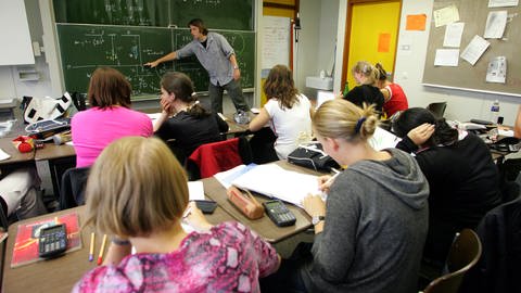 Beim Physikunterricht an einer Freiburger Schule erklärt ein Lehrer seiner Klasse an der Tafel Formeln (Archivbild). 