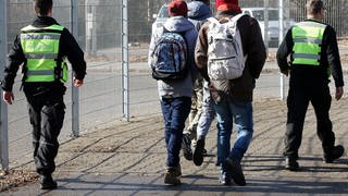 Mitarbeiter einer Sicherheitsfirma begleiten auf dem Gelände der Erstaufnahmestelle in Sigmaringen eine Gruppe von Asylbewerbern (Archivbild).