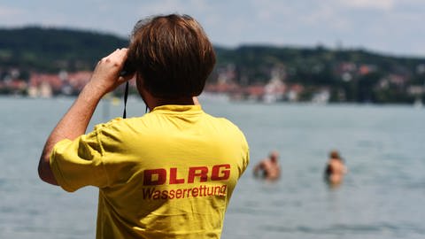 Ein Rettungsschwimmer der Deutschen Lebensrettungsgesellschaft (DLRG) beobachtet bei Wallhausen (Baden-Württemberg) am Strandbad Schwimmer im Bodensee.