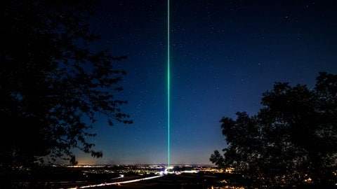 Ein grüner Laser, der in den Himmel ragt.