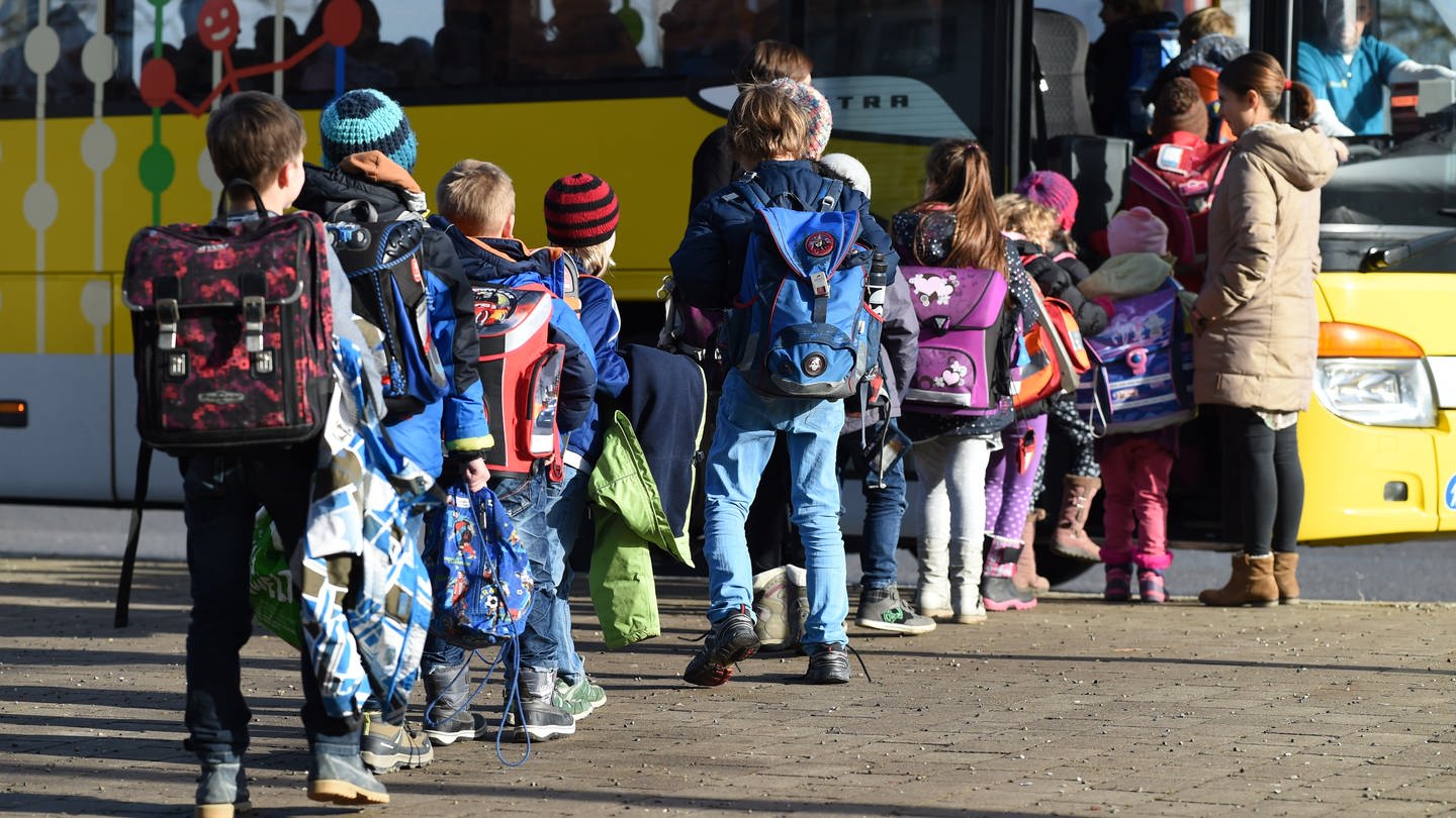 Mehrere Schüler steigen in einen Schulbus ein.