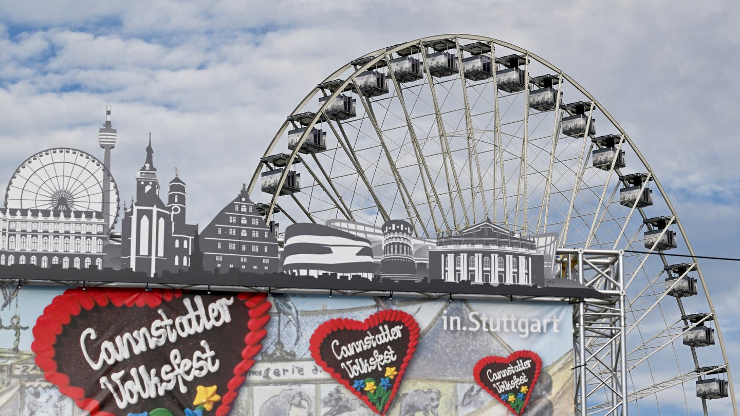 Ein Riesenrad steht zwei Tage vor der Eröffnung des 176. Cannstatter Volksfests hinter dem Logo des Eingangsportals auf dem Festgelände.