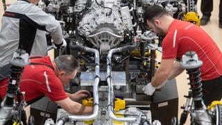 Mitarbeiter der Porsche AG montieren im Hauptwerk den Motor eines Porsche 911. Auto- und Zulieferindustrie: Von gefährdeten Jobs hin zu neuen Berufen