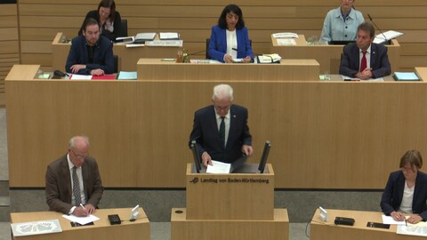 Ministerpräsident Winfried Kretschmann steht am Rednerpult im baden-württembergischen Landtag. Er hält eine Rede zum Angriff der Hamas auf Israel. Hinter ihm ist Landtagspräsidentin Muhterem Aras zu sehen.