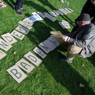 Harry Widmann, Delegierter des Netzwerk 1 der Landesarmutskonferenz Baden-Württemberg, legt während einer Fotoaktion der Landesarmutskonferenz im Jahr 2022 zu Beginn der landesweiten Aktionswoche "Armut bedroht alle" Pappbuchstaben aus.