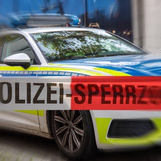 Symbolbild: Polizeiabsperrung mit Polizeiauto im dahinter 