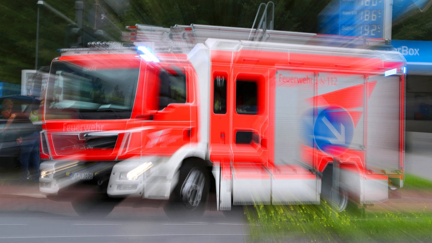 Feuerwehreinsatz im Kölner Stadtteil Höhenberg - Ein Löschfahrzeug der feuerwehr fährt mit Blaulicht durch eine Straße zu einem Einsatz