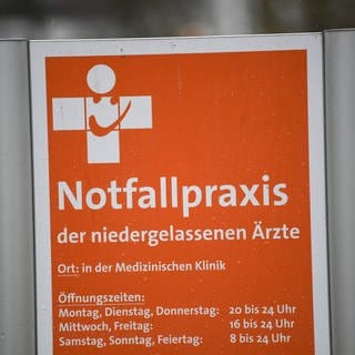 Ein Schild mit der Aufschrift "Notfallpraxis der niedergelassenen Ärzte" steht vor einem Gebäude an der Universitätsklinik Freiburg.