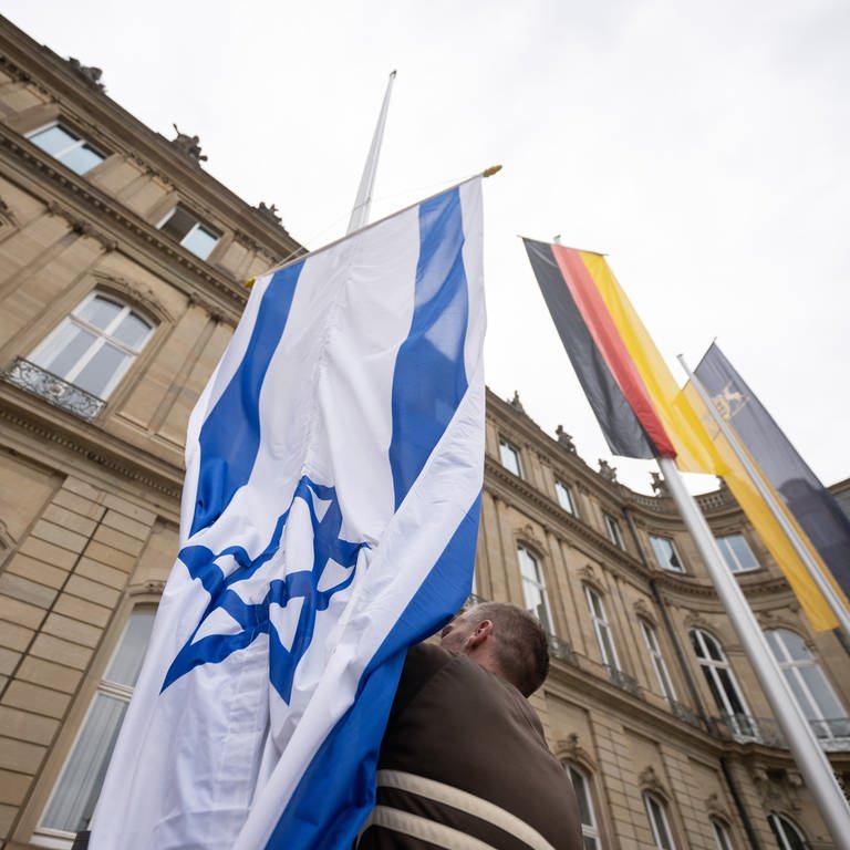 Die Flagge Israels wird von einem Mitarbeiter des Staatsministeriums Baden-Württemberg zwischen den Flaggen der EU, Deutschlands und Baden-Württembergs gehisst. 
