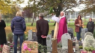 Allerheiligen auf dem Friedhof: Priester mit Personen