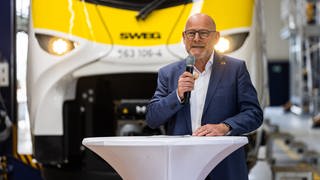 Winfried Hermann (Grüne), Landesverkehrsminister von Baden-Württemberg, steht im Juni 2023 vor einem neuen, batterieelektrisch betriebenen Zug in einem neuen Depot der SWEG (Südwestdeutsche Landesverkehrs-GmbH) in Offenburg.