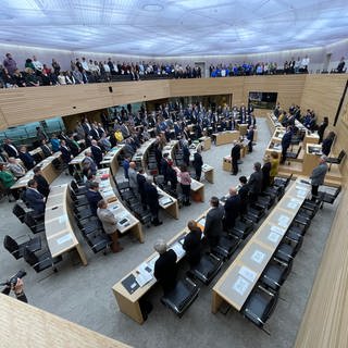 Abgeordnete und Besucher des Landtags von Baden-Württemberg stehen bei einer Schweigeminute für alle Opfer antisemitischer Verbrechen anlässlich einer Debatte zum Kampf gegen Antisemitismus im Plenarsaal in Stuttgart. 