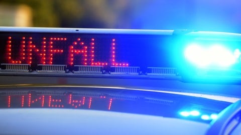 Ein Polizeiauto mit eingeschaltetem Blaulicht und dem Schriftzug "Unfall"