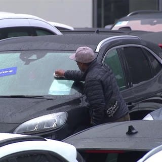 Mann putzt Scheibe eines Autos