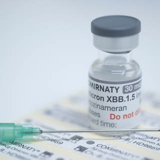 Eine Ampulle mit 6 Dosen des neuen an die Omikron-Sublinie XBB.1.5 angepassten Corona-Impfstoffs steht auf einem Tisch in einer Apotheke.