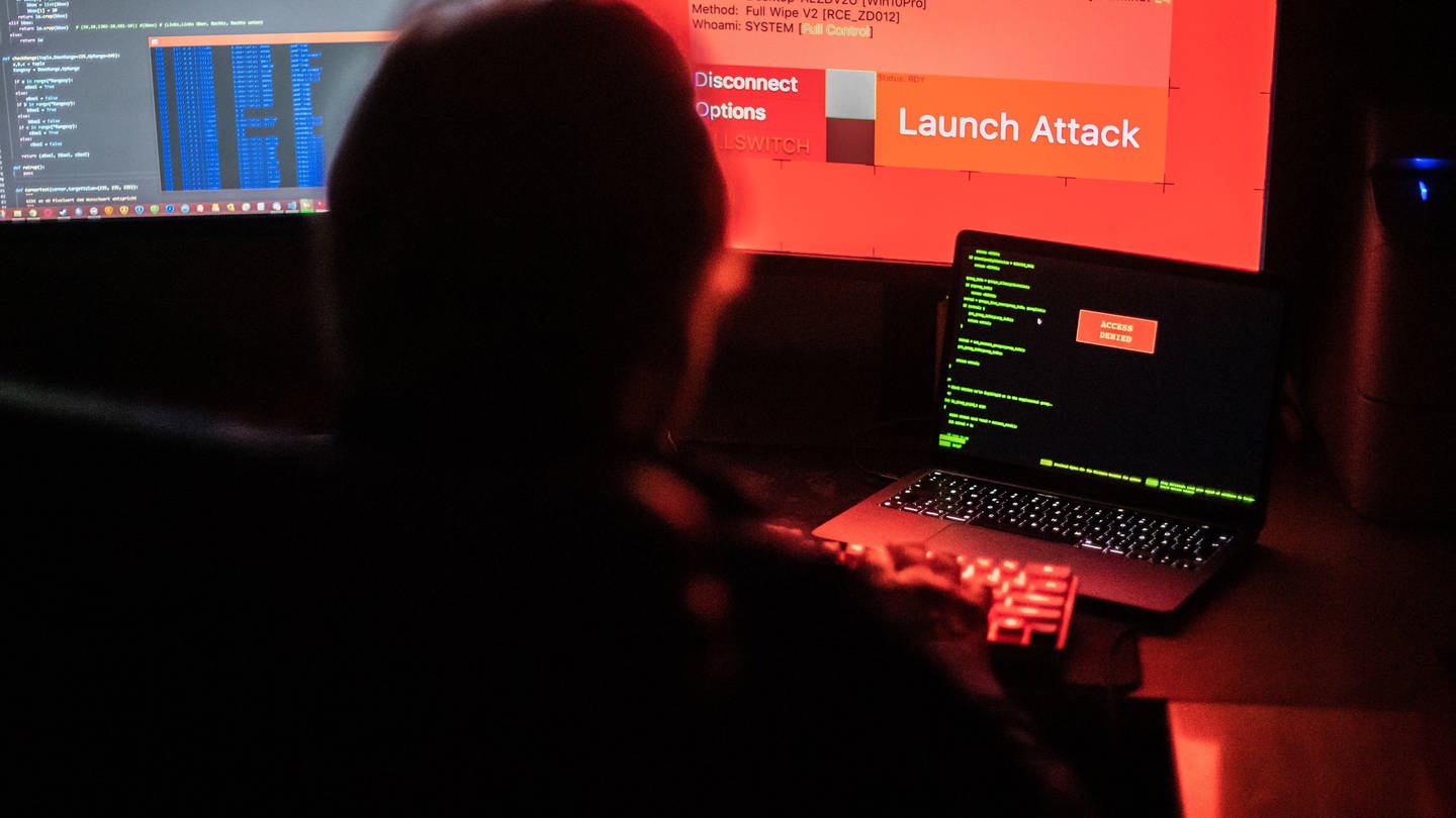 Hacker vor Bildschirm und Computern