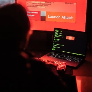Hacker vor Bildschirm und Computern