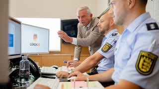 homas Strobl (l, CDU), Innenminister von Baden-Württemberg, sieht sich im Lagezentrum der Polizei im Innenministerium die Arbeit von Polizeieinheiten an, die in diesem Moment mit der Simulation eines großen Cyberangriffs beschäftigt sind.