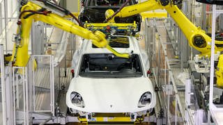 Roboter kleben die Front- und Heckscheibe in einen Porsche Macan im Leipziger Porsche-Werk ein.
