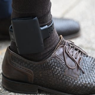 Ein Mann trägt zu Demonstrationszwecken eine elektronische Aufenthaltsüberwachung, bekannt als elektronische Fußfessel. 