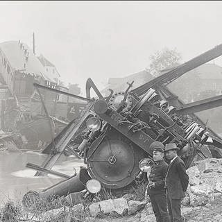 eine Schwarz-Weiß-Aufnahme einer zerstörten Brücke mitsamt entgleistem Zug