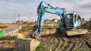 Ein Bagger steht in einem Baugebiet auf einem Bauplatz. Die Suche nach einem Baugrundstück ist in Baden-Württemberg schwer.