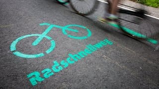 Radfahrer fahren auf dem Radschnellweg zwischen BöblingenSindelfingen und Stuttgart an einer Aufschrift auf dem Asphalt vorbei. (Archivbild)
