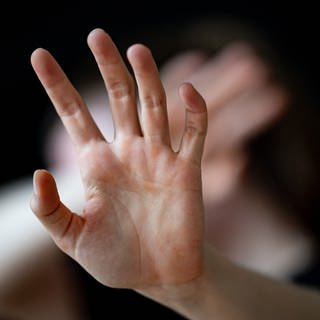 Eine Frau hält ihre Hände vor das Gesicht.