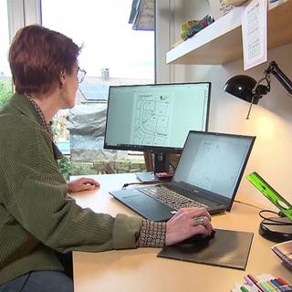 Frau vor PC und Notebook am Schreibtisch