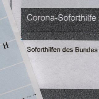 Ein Kontoauszug mit der überwiesenen Summe von 9.000 Euro Corona-Soforthilfe liegt auf einem Antrag für den Zuschuss.