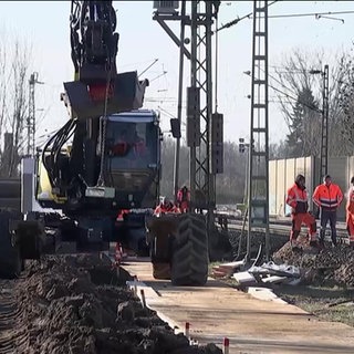 Bagger und Arbeiter während dem Sanieren einer Bahnstrecke