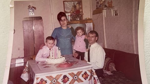 Familie mit Geburtstagstorte an einem Tisch