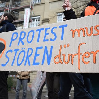 Klimaaktivisten der "Letzten Generation" protestieren vor dem Oberlandesgericht (OLG) Karlsruhe mit einem Plakat auf dem steht "Protest muss stören dürfen!". 