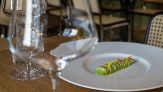 Eine nach Matjesart gebeizte Aubergine liegt im Sternerestaurant "bi:braud" auf einem Teller an einem leeren Tisch.