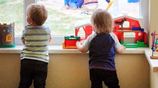 Zwei kleine Kinder spielen am Fenster in einer Kindertagesstätte.