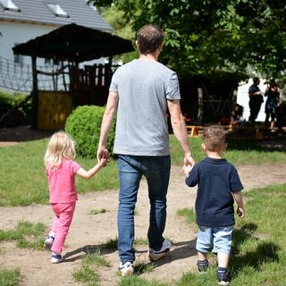 Ein Erzieher geht am 22.06.2016 im St. Michaels Kindergarten in Leinfelden-Echterdingen (Baden-Württemberg) mit zwei Kindern an den Händen.