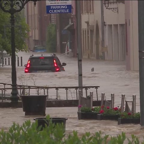 Auto steht auf einer überschwämmten Straße zur Hälfte im Wasser