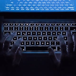 Ein Mann benutzt die beleuchtete Tastatur eines Notebooks (Szene gestellt)