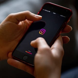 Auf dem Bildschirm eines Smartphones sieht man das Logo der App Instagram