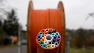 Eine Kabeltrommel mit Leitungen für Breitbandkabel steht auf einer Baustelle.